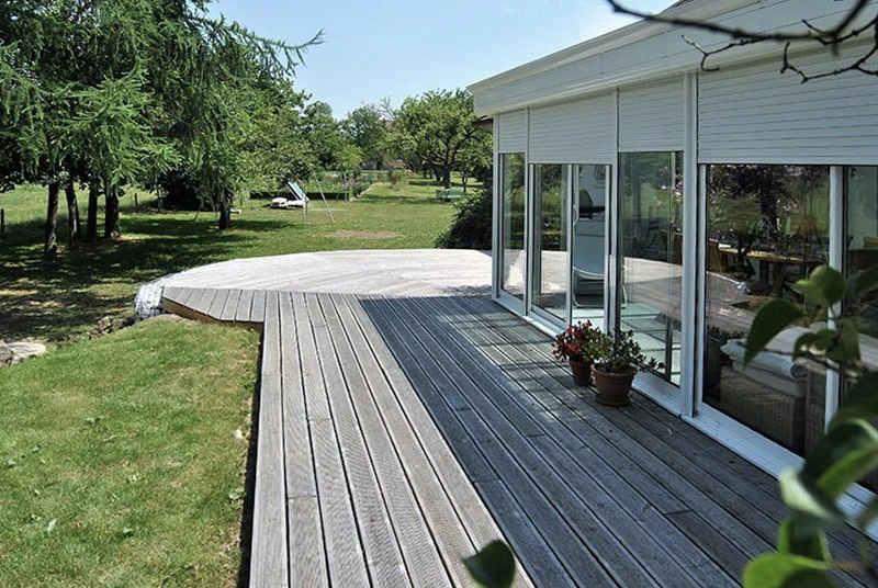 Terrasse extérieure d'une maison moderne avec véranda vitrée panoramique