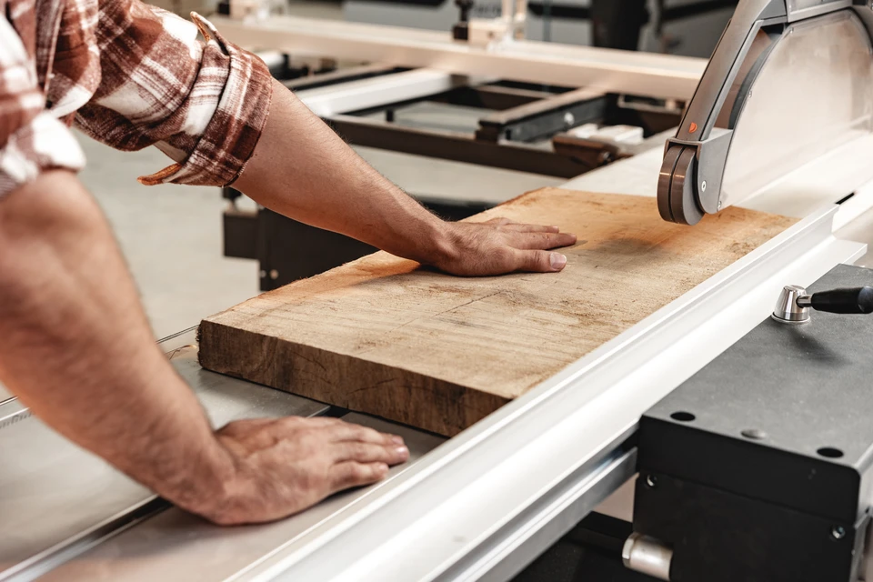 Quatre professionnels souriants consultent une tablette dans un atelier de menuiserie ou ébénisterie