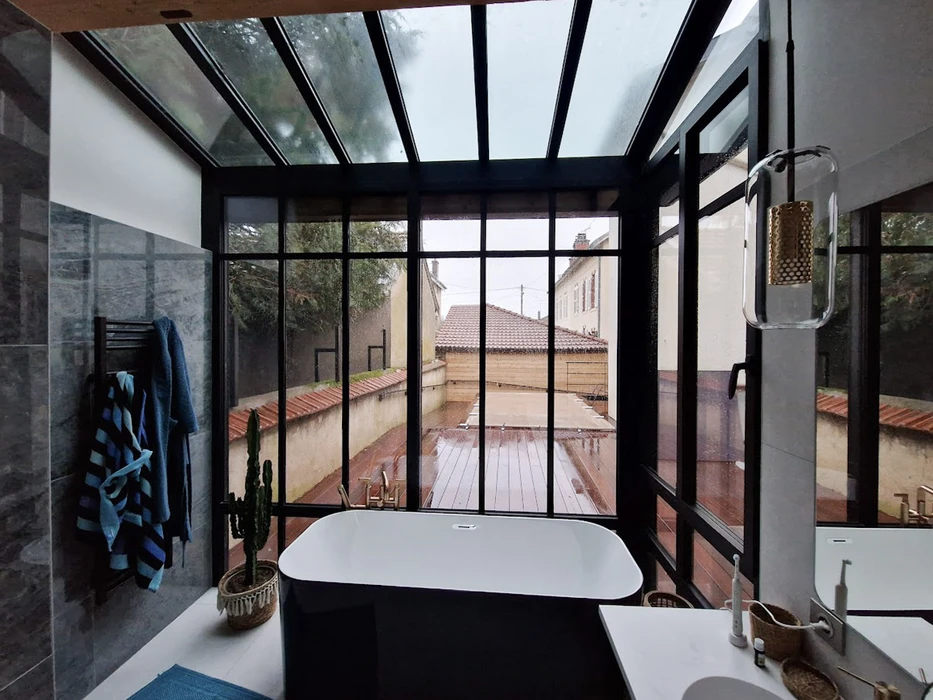 Terrasse extérieure d'une maison moderne avec véranda vitrée panoramique