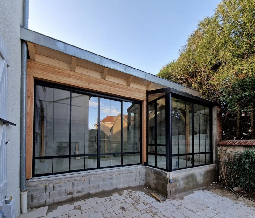 Terrasse extérieure d'une maison moderne avec véranda vitrée panoramique