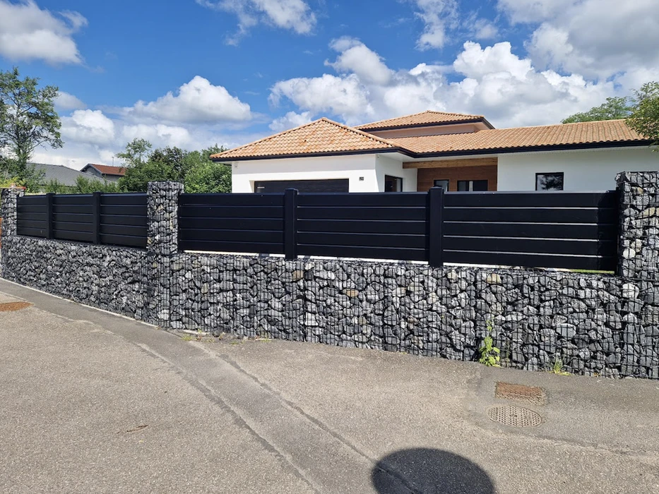 Clôture résidentielle moderne avec portail automatique coulissant gris anthracite, piliers en pierre naturelle beige, muret bas assorti