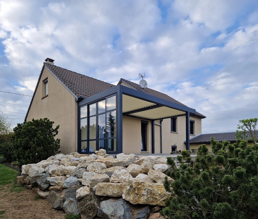 Extérieur d'une maison avec véranda vitrée panoramique et terrasse