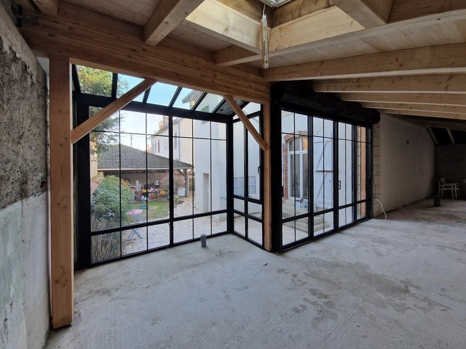 Espace extérieur résidentiel avec terrasse en bois composite, pergola à toiture polycarbonate translucide et structure métallique anthracite